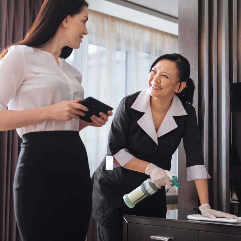 Joyful nice businesswoman talking to a hotel maid